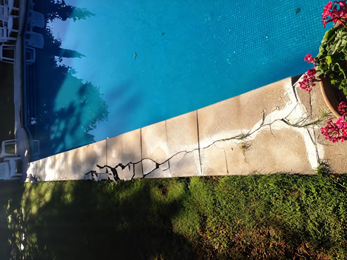 Broken and cracked coping along the edge of a swimming pool.