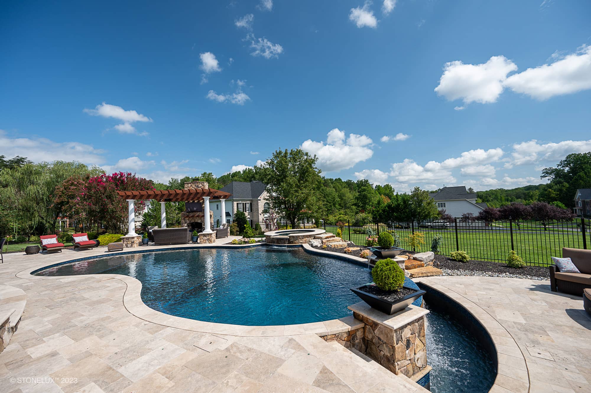 Luxurious outdoor scene featuring Walnut Travertine natural stone used as pool deck and coping. The design includes a sparkling blue pool, elegant pergola, and lush landscaping. Ideal for premium hardscape projects, enhancing modern outdoor aesthetics.