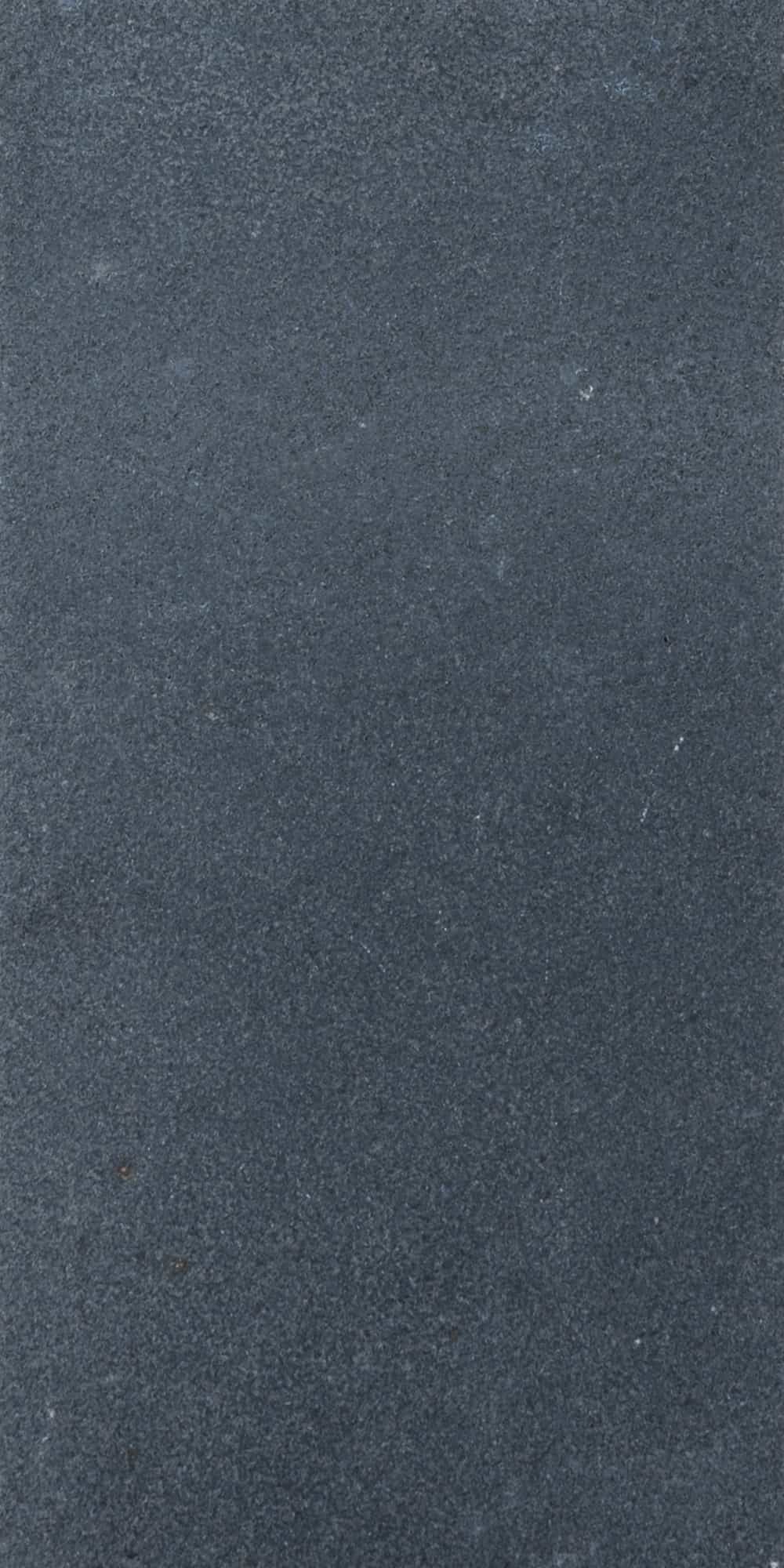 Close-up of Black Basalt Tumbled+Brushed 12x24 3cm Paver showcasing its natural stone texture. The basalt surface features a smooth, tumbled finish with subtle speckles, ideal for elegant hardscape projects and modern outdoor designs.