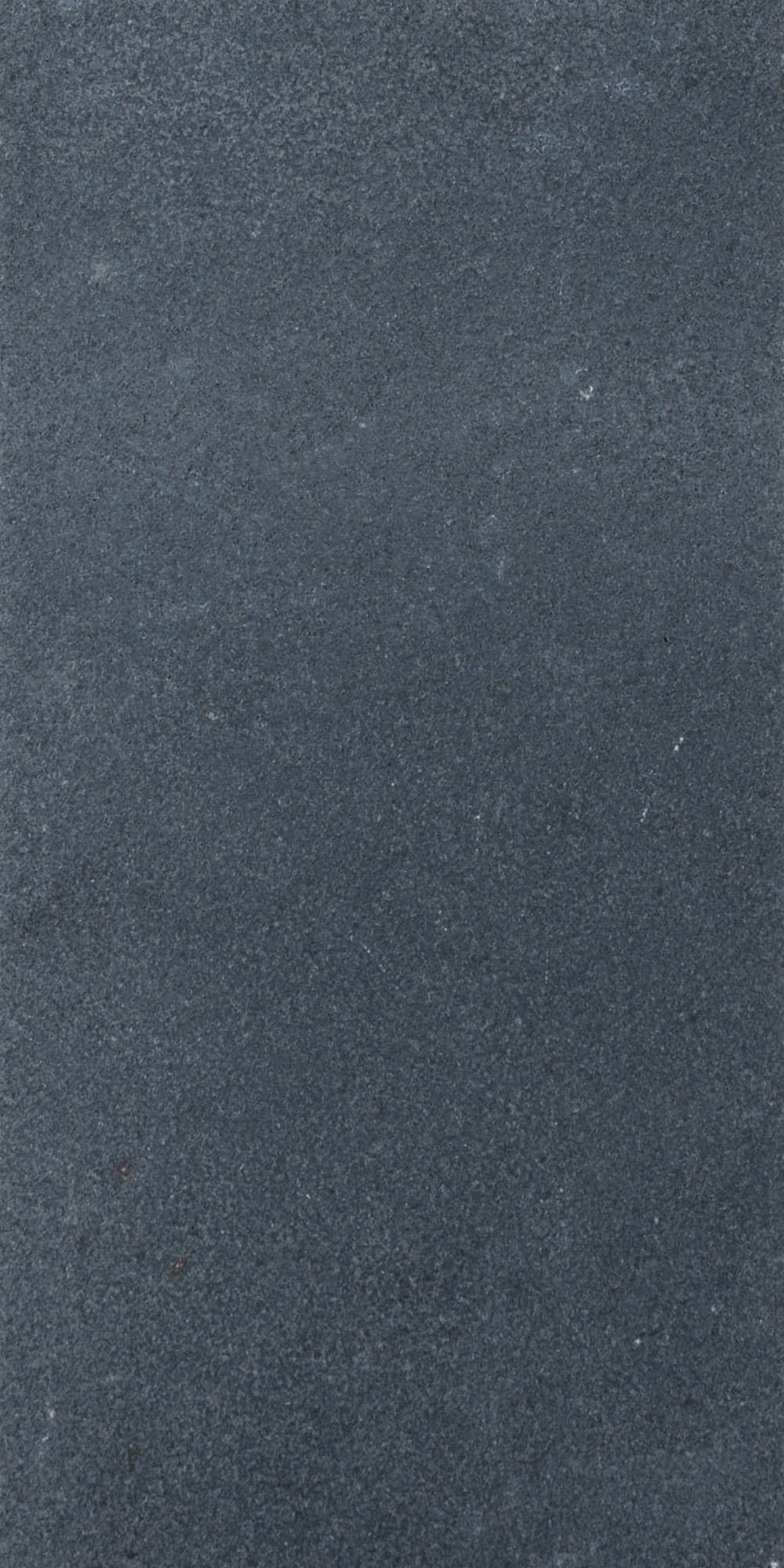 Close-up of the Black Basalt Tumbled+Brushed 8x16 3cm Paver by STONELUX, showcasing its dark gray, finely textured surface with a subtly tumbled finish. Ideal for hardscape projects, this natural stone paver offers a sleek, modern aesthetic.