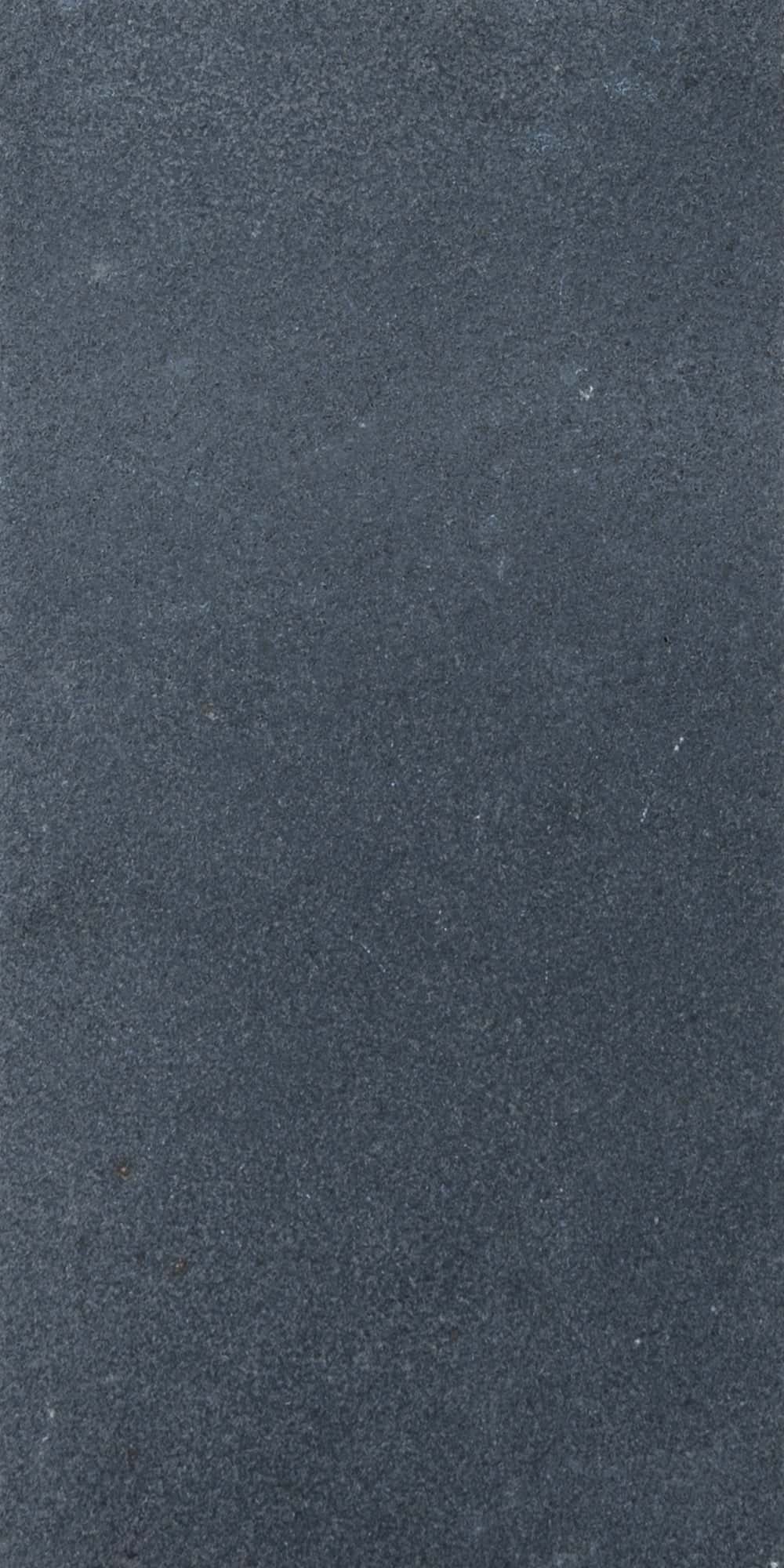 Close-up of the Black Basalt Tumbled+Brushed 8x16 3cm Paver by STONELUX, showcasing its dark gray, finely textured surface with a subtly tumbled finish. Ideal for hardscape projects, this natural stone paver offers a sleek, modern aesthetic.