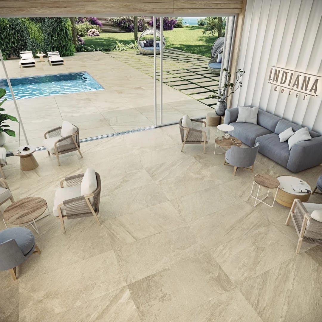 Indiana Beige Matte 24x48x2cm Rectified Porcelain Paver installed in a modern outdoor patio and pool area. The matte porcelain finish complements the luxurious seating, lush greenery, and serene blue pool, enhancing the elegant hardscape design.