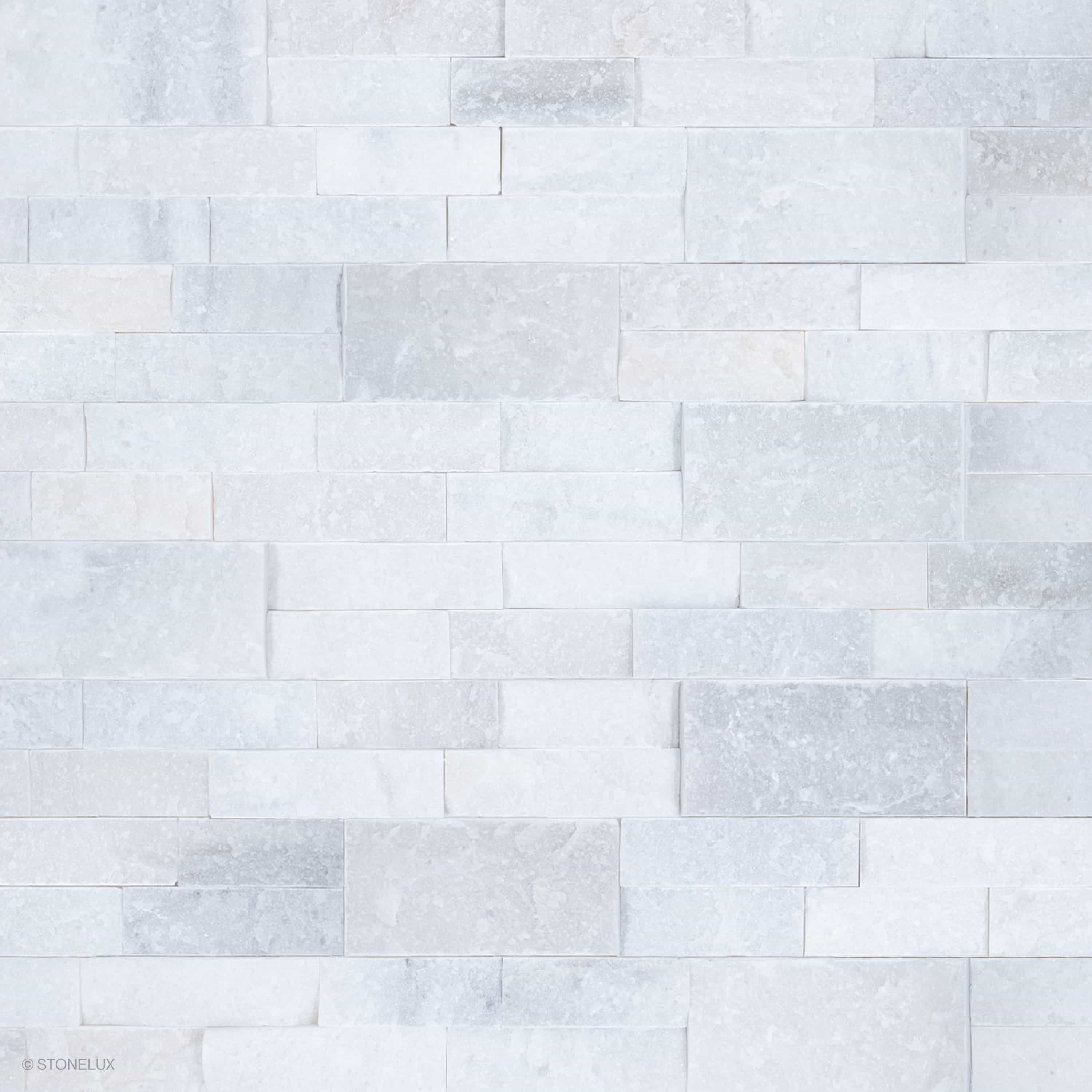 Close-up of Afyon White Marble Splitface Ledger Panel 6x24 by STONELUX, showcasing its textured splitface finish and elegant white and gray veining. Ideal for veneer wall projects, offering a timeless and luxurious aesthetic for interior and exterior d...