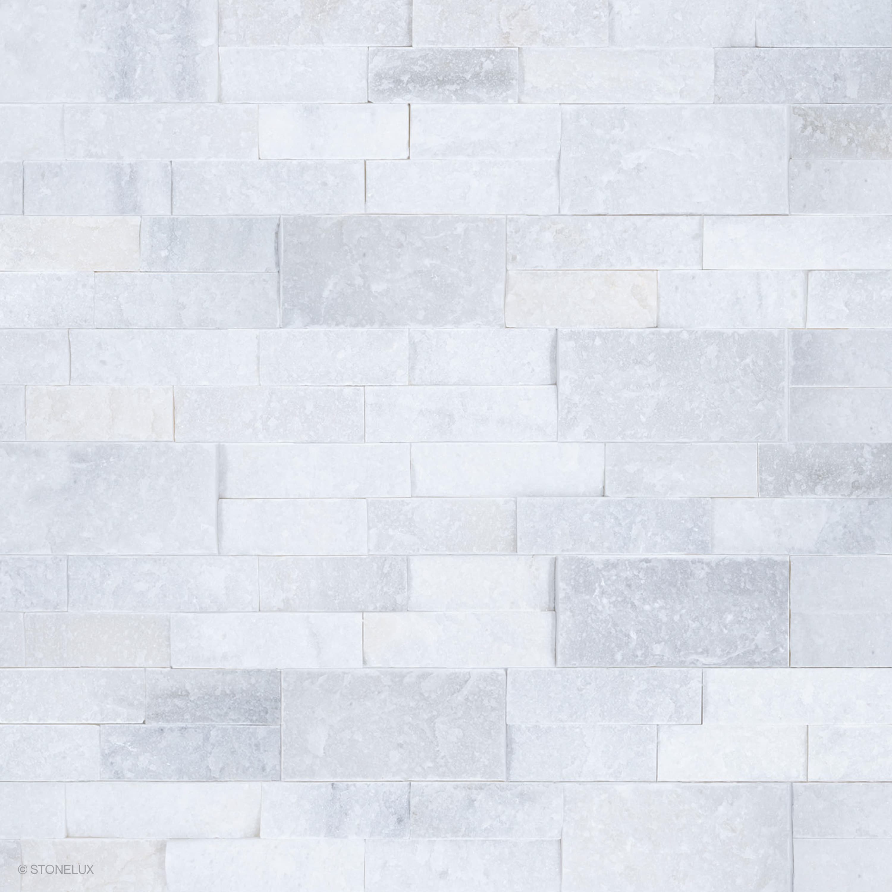 Close-up of Afyon White Marble Splitface Ledger Panel 6x24 by STONELUX, showcasing its textured splitface finish and elegant white and gray veining. Ideal for veneer wall projects, offering a timeless and luxurious aesthetic for interior and exterior d...