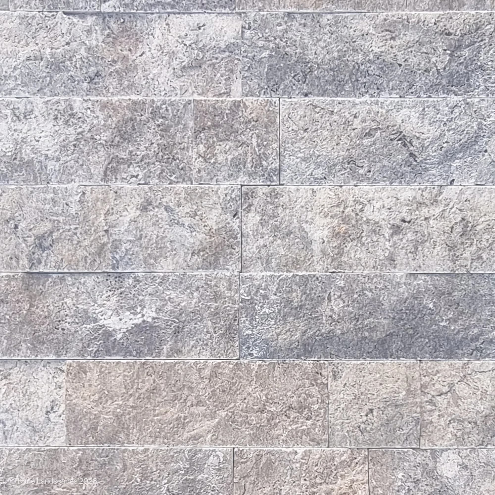 Close-up of Silver Travertine Splitface Veneer showcasing its textured surface with natural gray and silver tones. The 4" x Free Length tiles display unique veining and a rustic finish, ideal for contemporary or traditional hardscape and renovation pro...