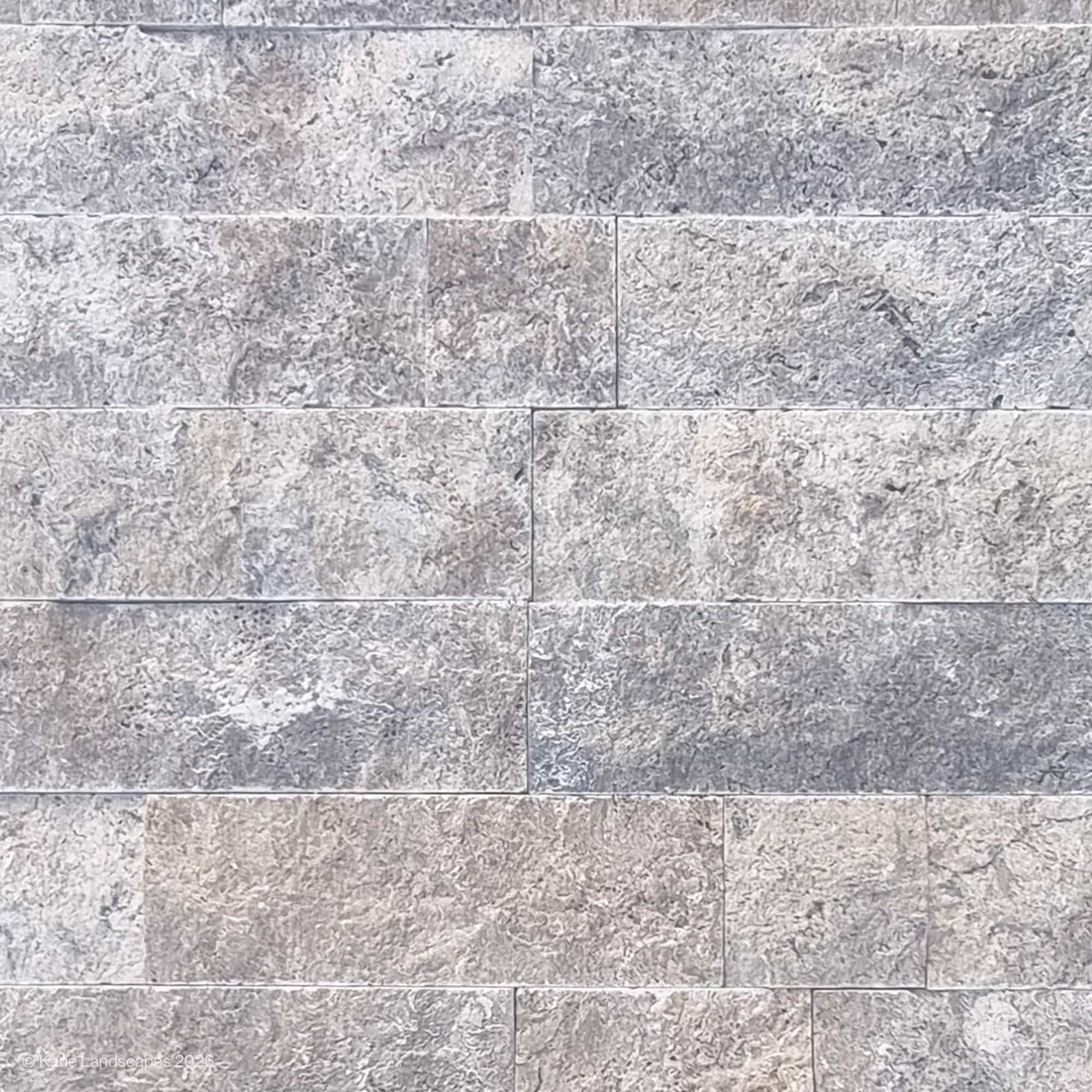 Close-up of Silver Travertine Splitface Veneer showcasing its textured surface with natural gray and silver tones. The 4" x Free Length tiles display unique veining and a rustic finish, ideal for contemporary or traditional hardscape and renovation pro...