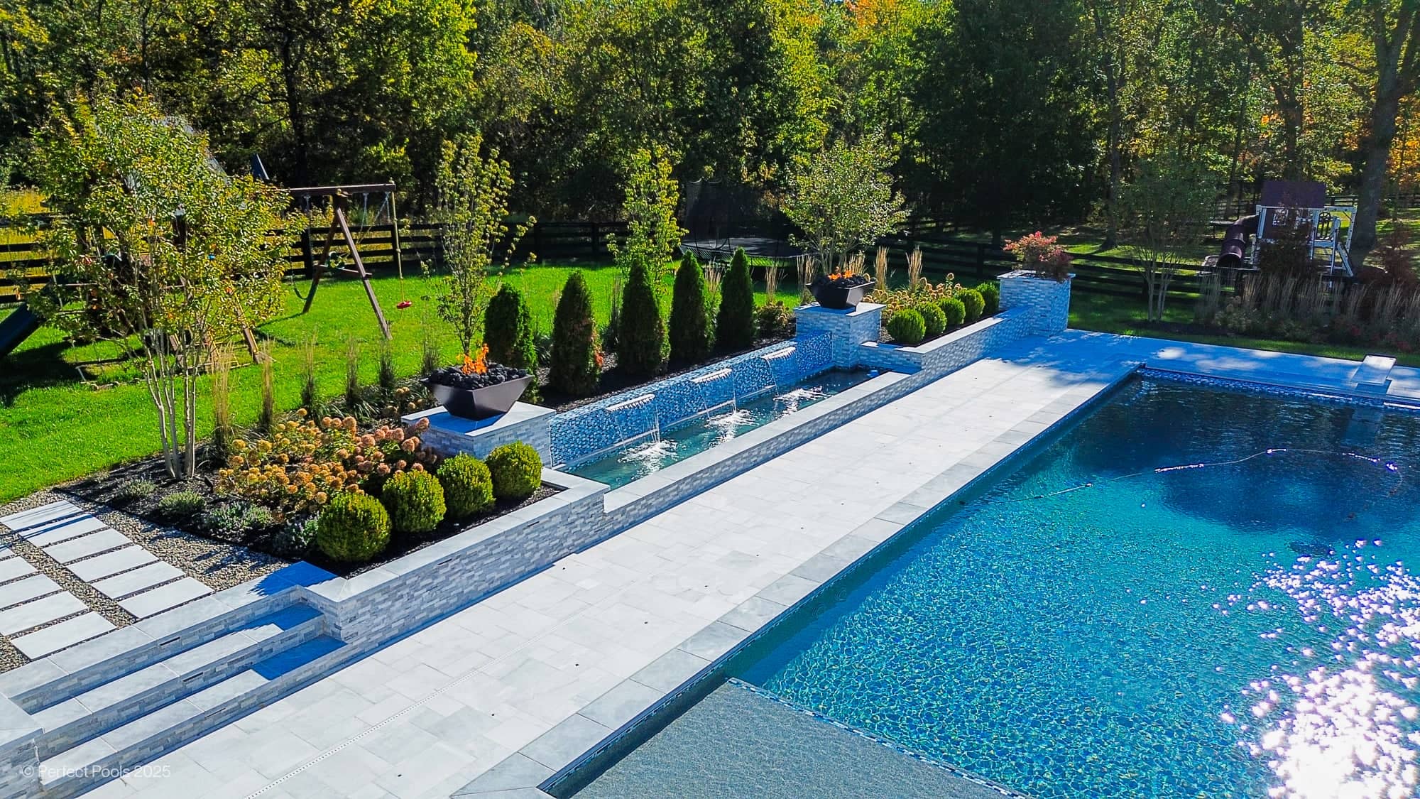 Luxury pool project in Aldie, VA featuring Aldie Serenity collection with Afyon White and Arctic Grey marble. The modern design includes elegant marble coping, crystal-clear pool water, lush landscaping, and sleek planters, creating a serene backyard o...