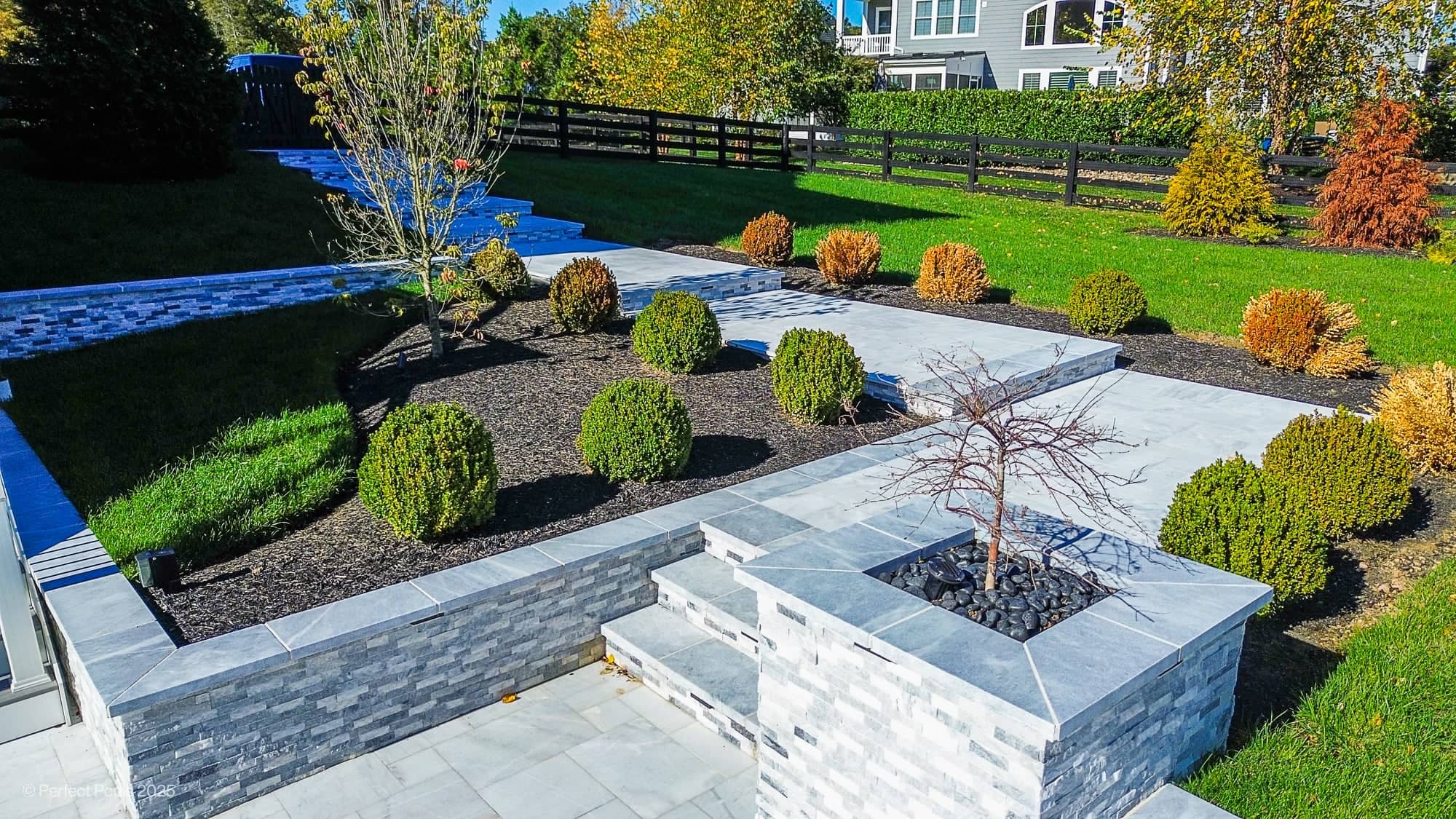 Aldie Serenity showcases Afyon White and Arctic Grey marble in a luxurious poolside setting. Modern design with sleek marble pavers, manicured shrubs, and vibrant greenery. The elegant landscape features layered stone planters, enhancing the serene bac...