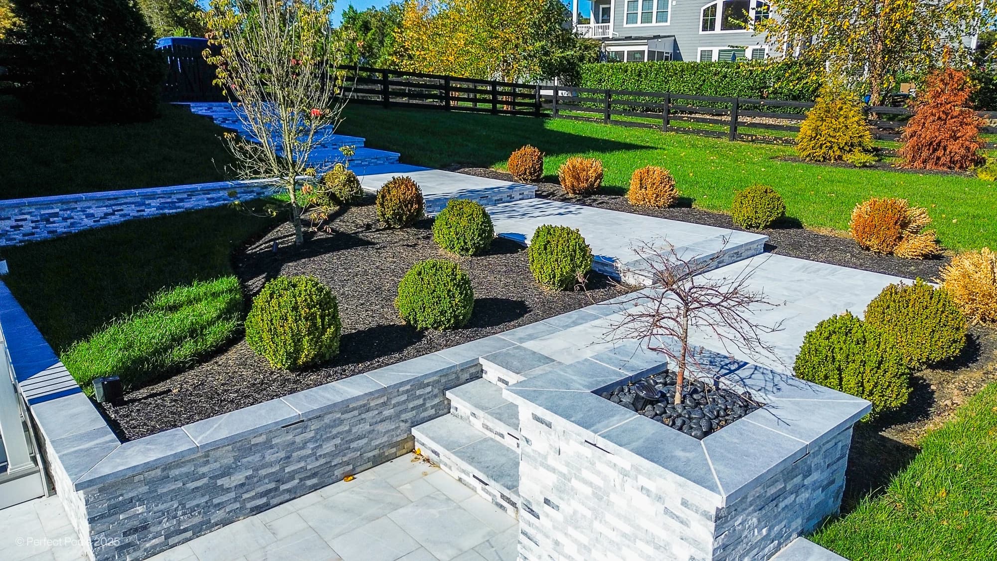 Aldie Serenity showcases Afyon White and Arctic Grey marble in a luxurious poolside setting. Modern design with sleek marble pavers, manicured shrubs, and vibrant greenery. The elegant landscape features layered stone planters, enhancing the serene bac...