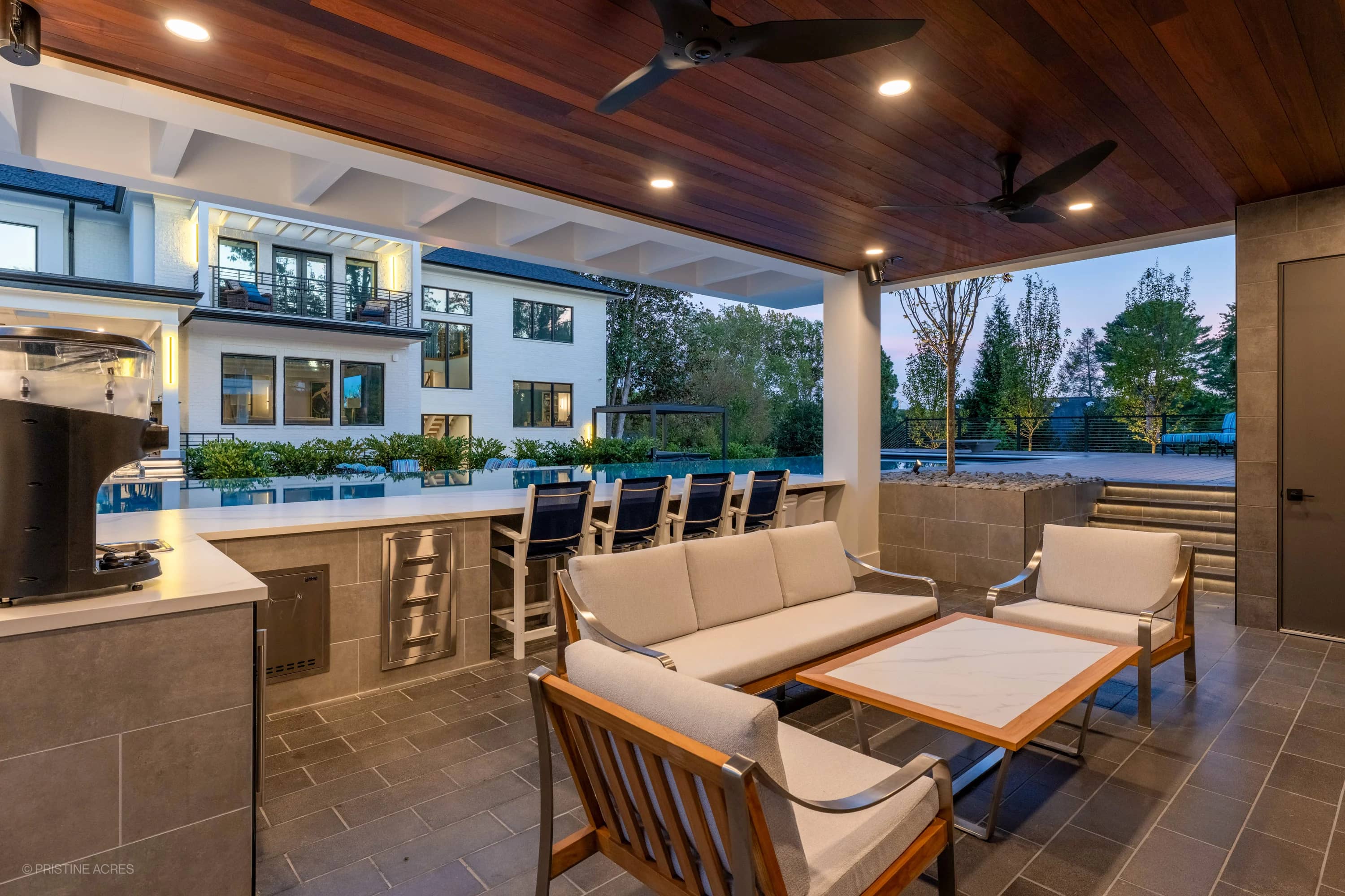 Modern McLean pool project featuring Black Basalt and Nexus White Porcelain collections. Contemporary design with sleek patio furniture, illuminated poolside, and lush landscaping in a luxurious backyard setting in McLean, VA.