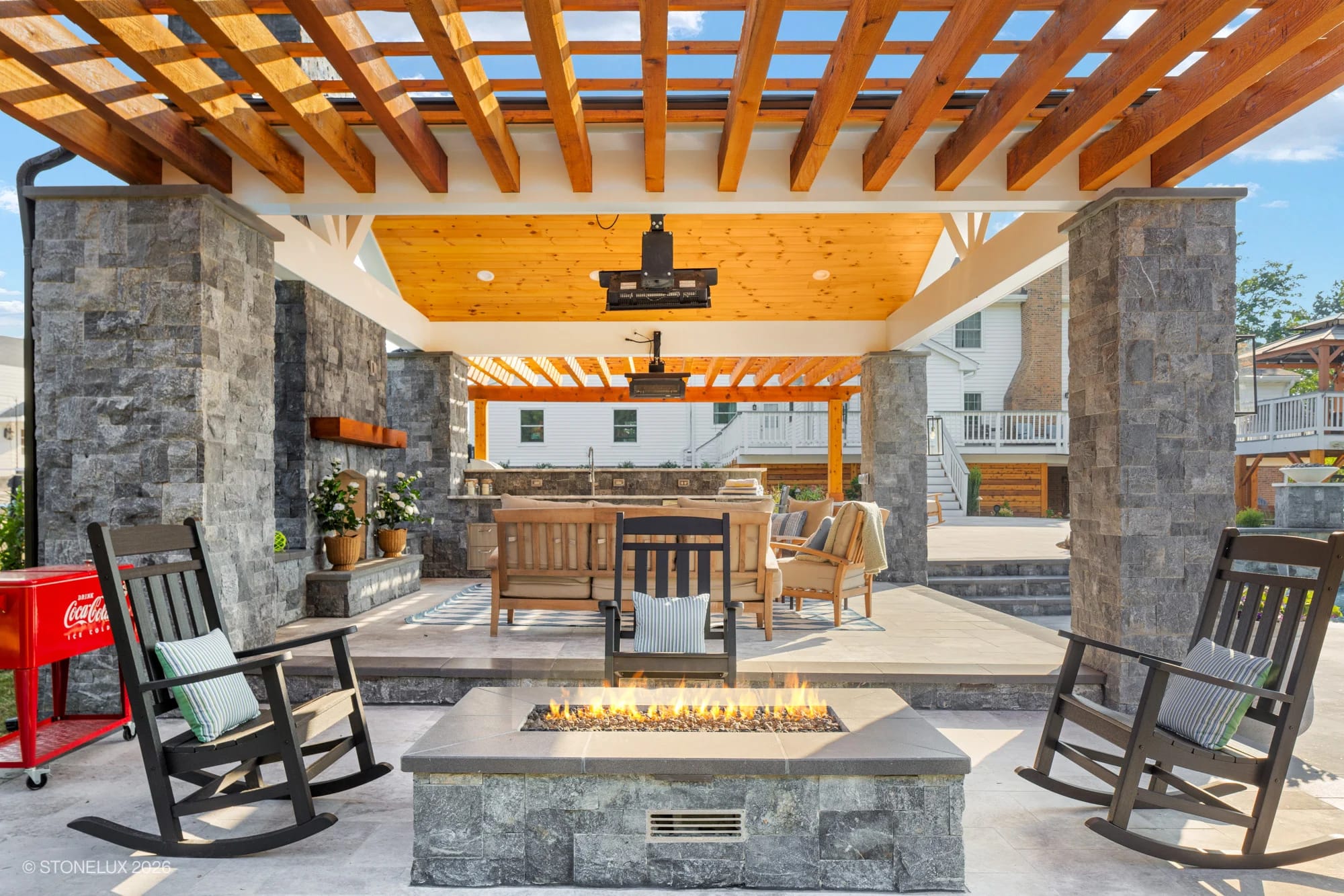 Modern backyard oasis in McLean, VA featuring Tundra Grey Marble and Black Basalt from the Afyon White Marble collection. Includes a cozy fire pit, wooden pergola, stylish patio furniture, and lush landscaping, creating a serene, luxurious ambiance.