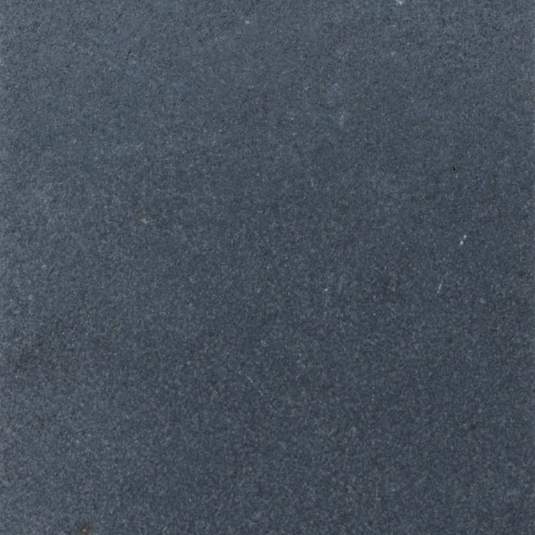 Close-up image of a rough, dark grey textured surface with subtle speckles and light abrasions scattered throughout, resembling Black Basalt natural stone.