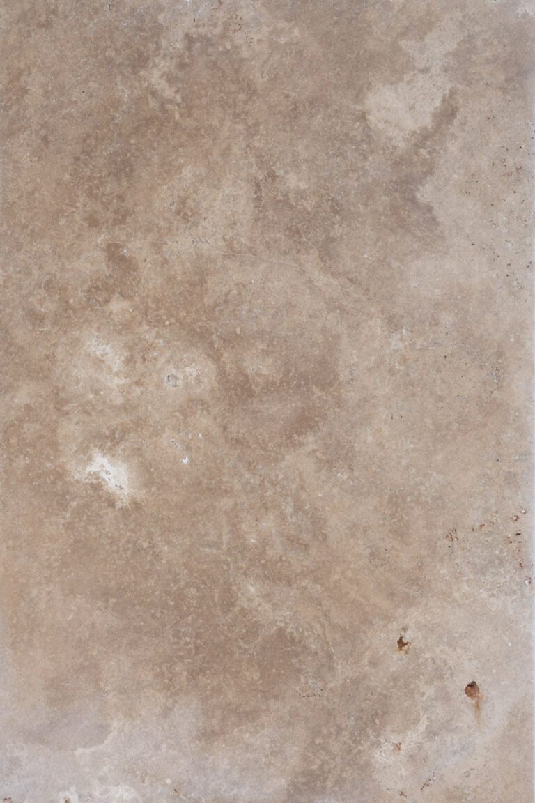 Textured surface of a Walnut Travertine Paver with natural patterns and slight imperfections, showcasing a detailed stone background.