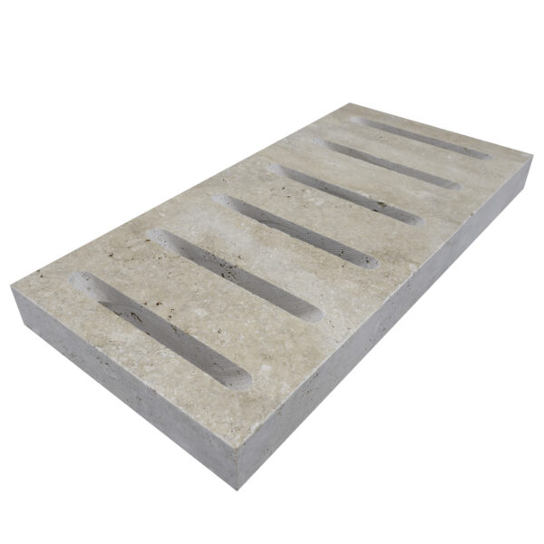 An Ivory Travertine Tumbled 6"x12"x3CM Drain Decor - Premium with five evenly spaced, elongated oval cutouts for exterior patio drain cover.
