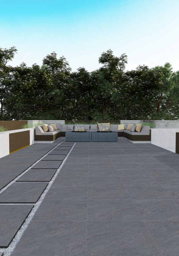 Modern outdoor terrace with Dakota Gray 24"x24" 2CM Matte Rectified Porcelain Paver flooring, featuring two beige sofas, a central coffee table, and a backdrop of lush green trees and plants.