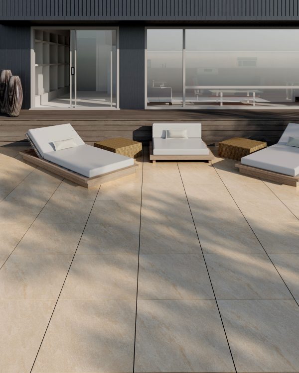 Modern rooftop terrace featuring stylish lounge chairs and sofas on Dakota Beige 24"x24" 2CM Matte Rectified porcelain paver flooring, with wood-paneled exterior walls and clear railings under a bright sky.