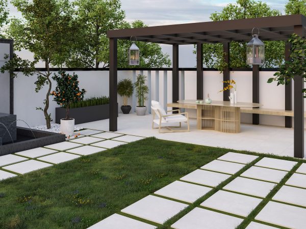 Modern garden patio featuring a Nexus White 24"x24" 2CM Matte Rectified Porcelain Paver walkway with grass gaps, pergola, outdoor dining table, chairs, lush plants, and boundary walls. Evening setting with hanging lanterns.