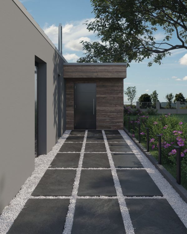 Modern home entrance featuring a geometric pathway comprised of alternating dark stone slabs and Onda Anthracite 24"x48" 2CM Matte Rectified Porcelain Pavers, leading to a sleek grey door, set against wooden and grey walls under a clear sky.