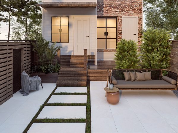 Modern home entrance with wooden steps leading to a white and brick front door, surrounded by lush green plants and a cozy outdoor swing with cushions on an Onda Pearl 24