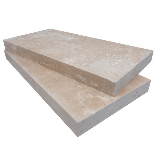 Two large, rectangular Ivory Travertine Tumbled 12"x24"x2" eased edge copings, stacked one on top of the other, isolated on a white background.