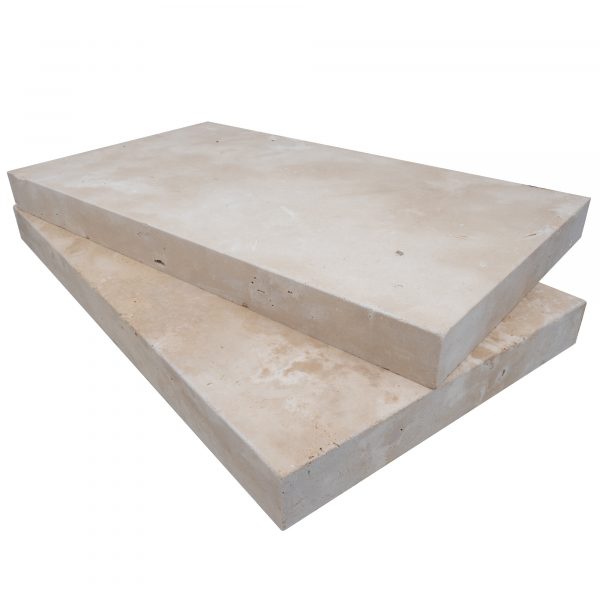A stack of two Premium Ivory Travertine Tumbled 14"x24"x2" Eased Edge Copings on a plain background, forming a simple, sturdy horizontal platform, with visible textures and markings.