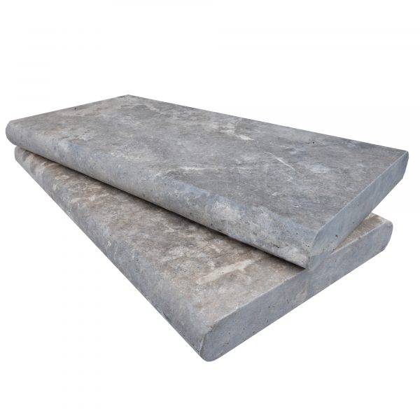 Two Silver Travertine Tumbled 12"x24"x2" Double Bullnose Copings stacked on top of each other, isolated on a white background. The copings show natural textures and imperfections typical of silver travertine.
