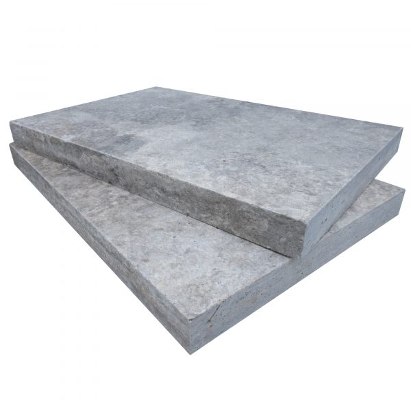 Two large Silver Travertine Tumbled 12"x24"x2" Eased Edge Copings stacked on top of each other, isolated on a white background. The slabs are rough-textured and appear sturdy.