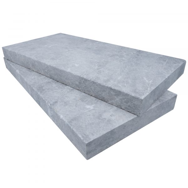 Two large, rectangular Tundra Grey Marble Sand Blasted 12"x24"x2" Eased Edge Copings stacked on top of each other isolated on a white background.