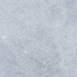 Textured surface of Tundra Grey Marble with subtle patterns of scratches and white speckles, giving an overall rough and gritty appearance.