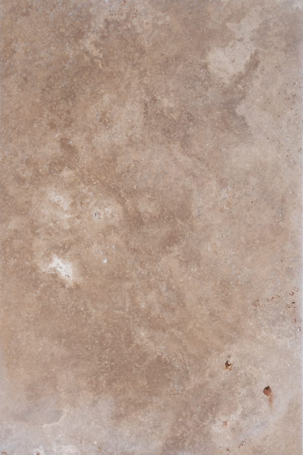 Textured surface of a Walnut Travertine Tumbled 16x24 3cm Paver - Premium with natural patterns and a few darker spots.